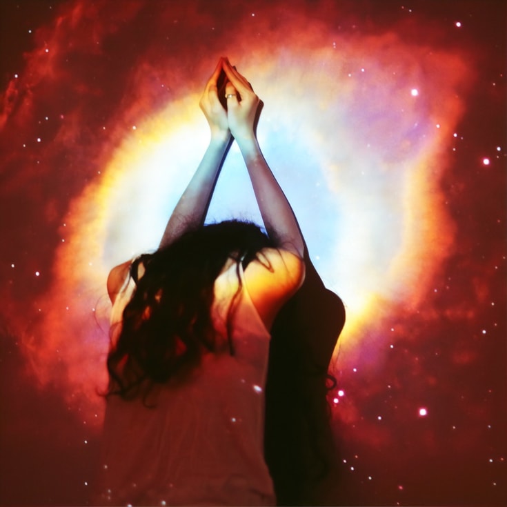 woman meditating surrounded by galaxy