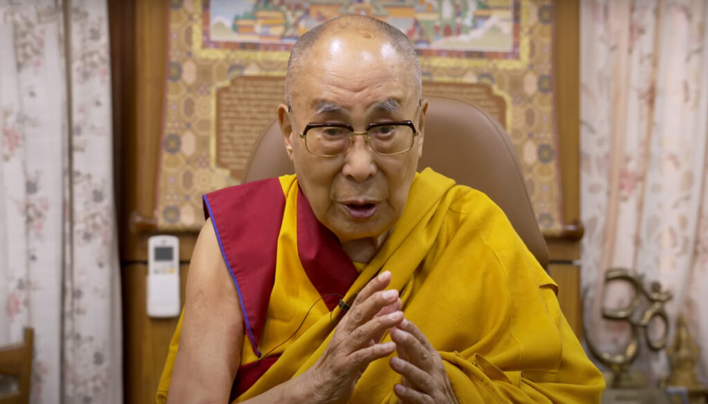 The Dalai Lama sits in a brown chair delivering his brithday message