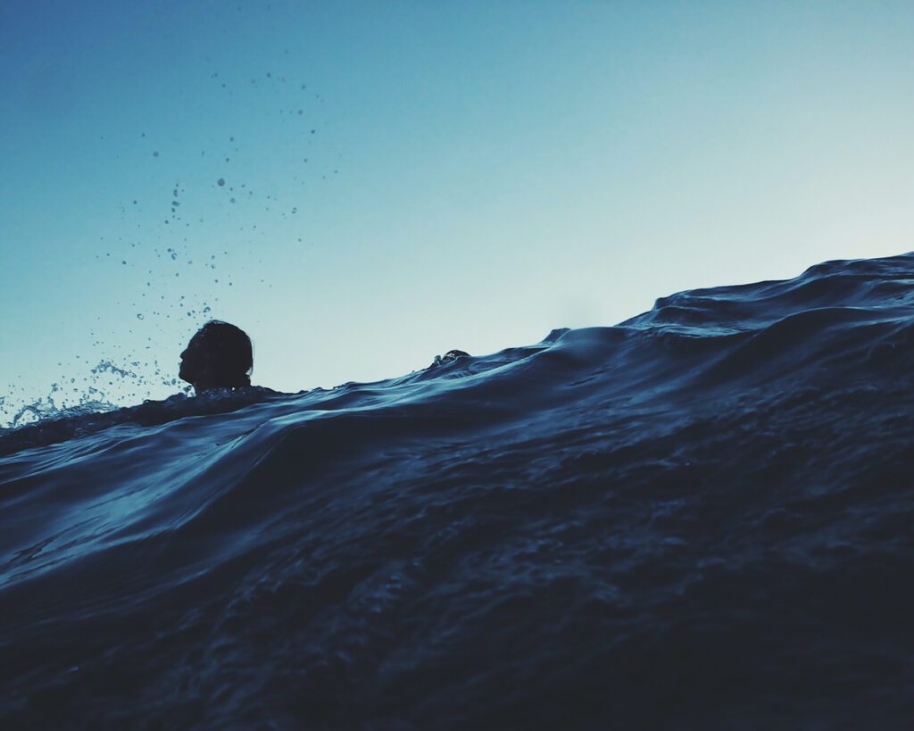 A swimmer tries to stay afloat within a wave.