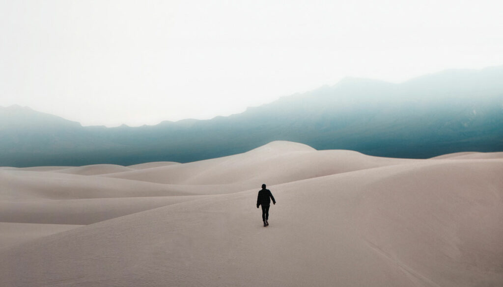 Person walking on cold sand dunes.