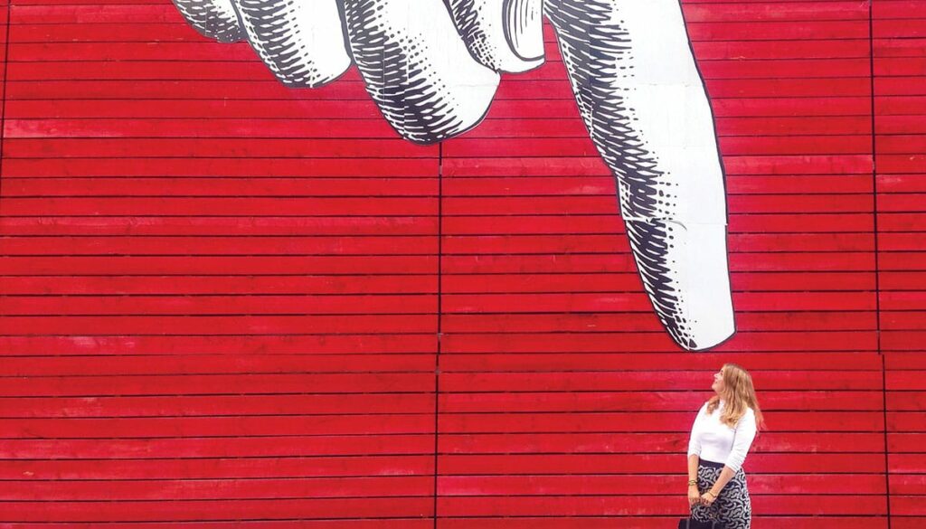 woman in front of pointing graffiti